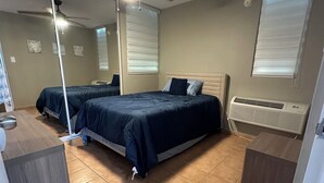A bedroom with two beds, a ceiling fan, a radiator, and a large mirror.