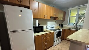 A kitchen with wooden cabinets, a white refrigerator, a stove, and a sink.