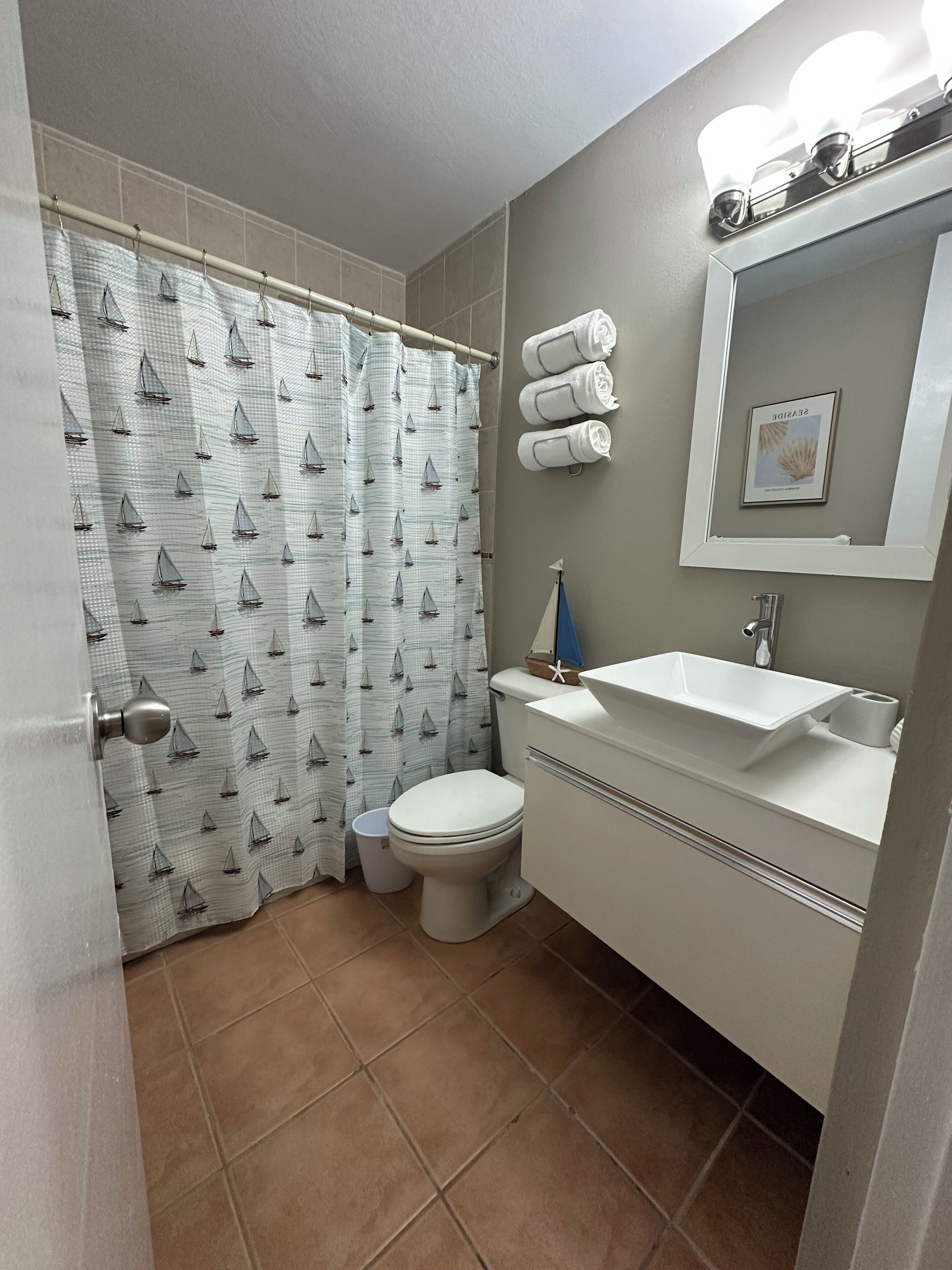 Modern nautical-themed bathroom with vessel sink and clean beachy decor.