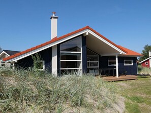 Ein modernes Haus mit rotem Dach, großen Fenstern und einem Schornstein.