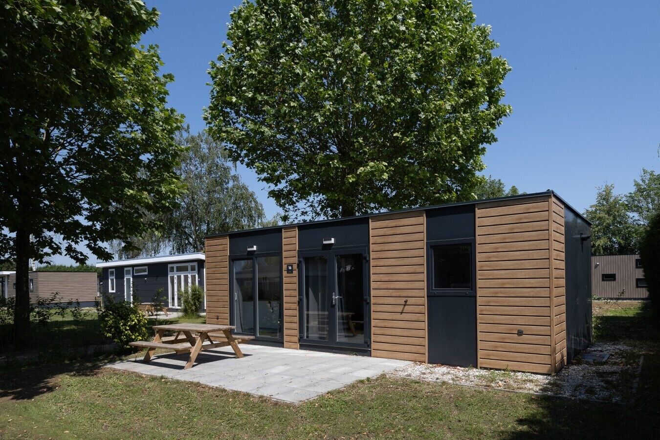 A modern, single-story building with a flat roof, large glass windows, and a wooden exterior.