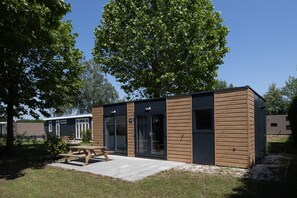 Ein modernes, eingeschossiges Gebäude mit Flachdach, großen Glasfenstern und Holzfassade.