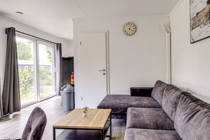 Een moderne woonkamer met een bank, een bijzettafeltje en een klok aan de muur.