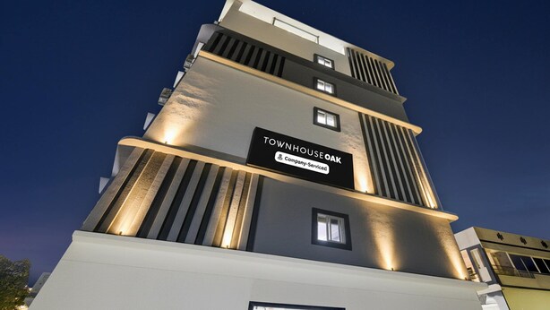 Un immeuble à plusieurs étages portant une enseigne indiquant : « Townhouse Oak Company – Services inclus ».