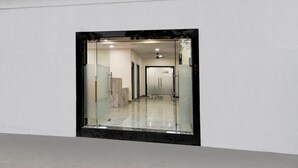 Un couloir avec un mur en verre, un ventilateur de plafond et un sol en marbre.
