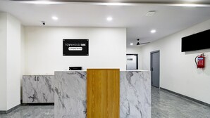 Un comptoir d’accueil avec un plateau en marbre et un panneau en bois, une enseigne au-dessus, un extincteur et une porte en arrière-plan.