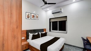 Une chambre à coucher comprenant un lit, un bureau, une chaise, un ventilateur de plafond et un appareil de climatisation.