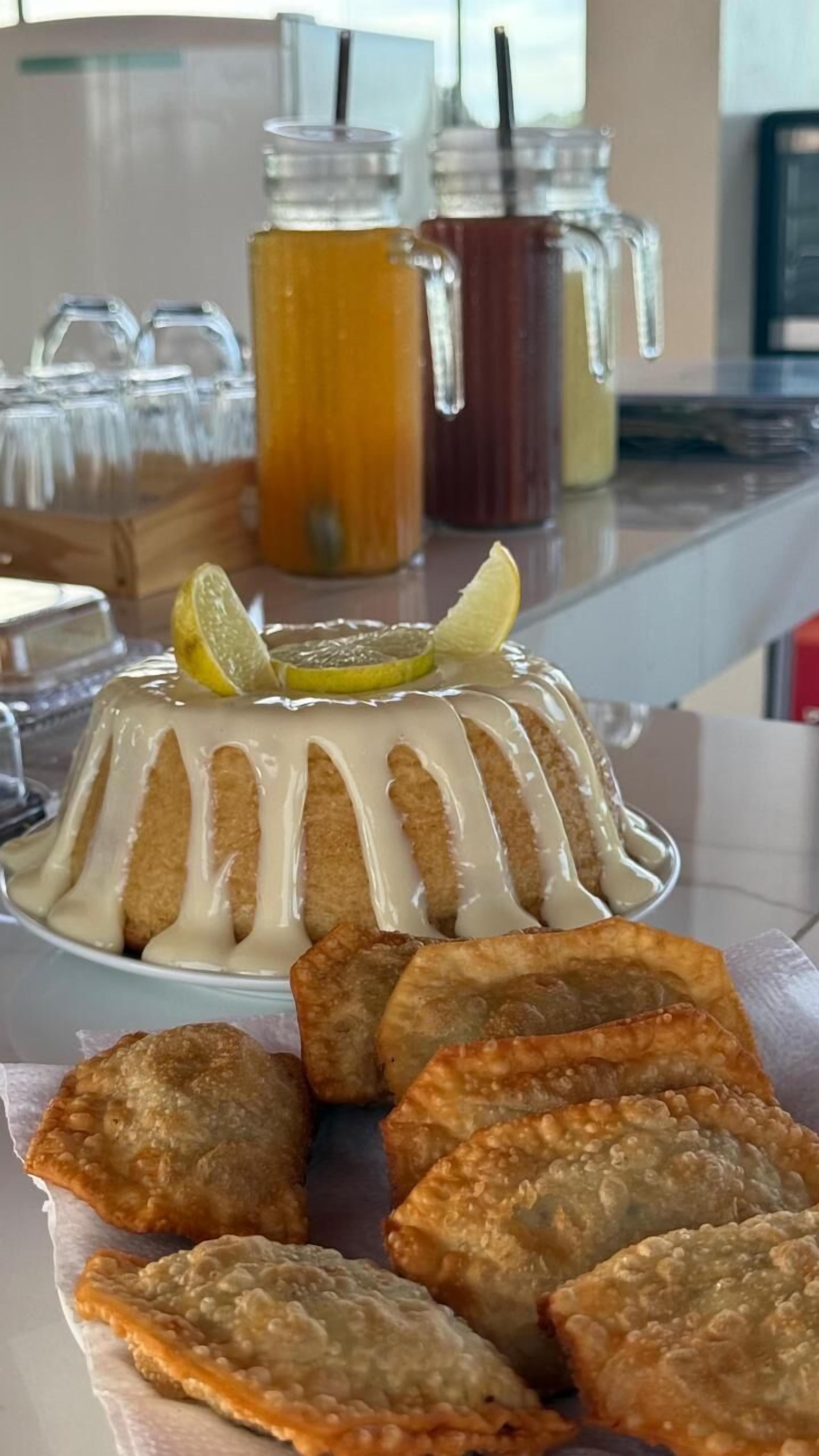 Un postre con una rodaja de limón encima, rodeado de hojaldres fritos en un plato.