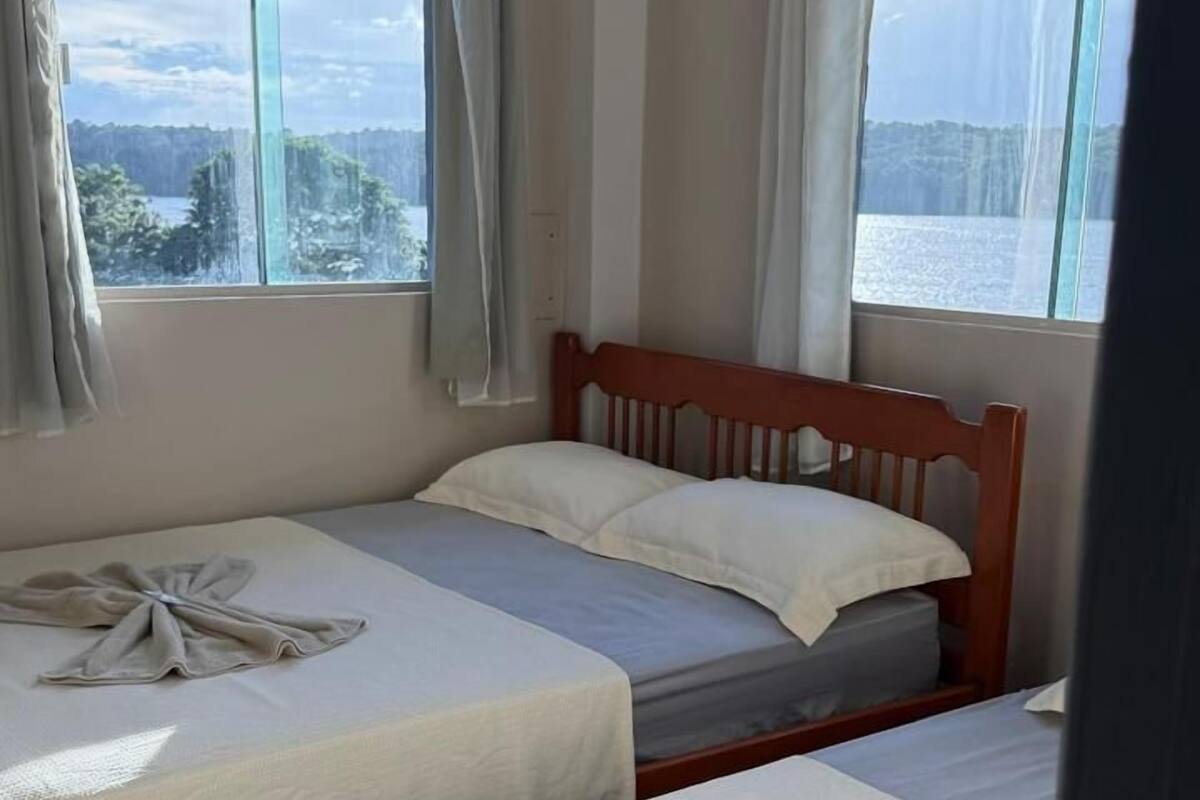 Une chambre d’hôtel avec deux lits, une grande fenêtre donnant sur un beau paysage et un appareil de climatisation.