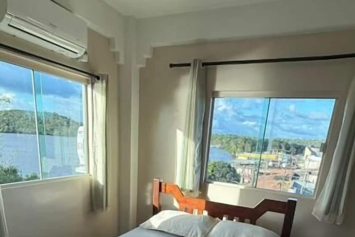 Une chambre d’hôtel avec un lit, deux fenêtres et une vue sur un paysage.