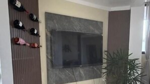 A room with a tiled floor, a wall-mounted TV, a potted plant, and a shoe rack with several pairs of shoes. - Hotel beira rio OPK (Oiapoque)