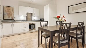 Een moderne keuken met witte kasten, een eettafel met stoelen en een bloemenvaas.