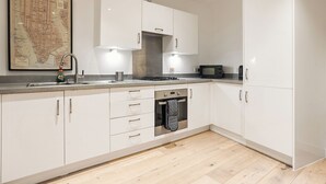 Een moderne keuken met witte kasten, een roestvrijstalen afzuigkap, een magnetron en een vaatwasser.