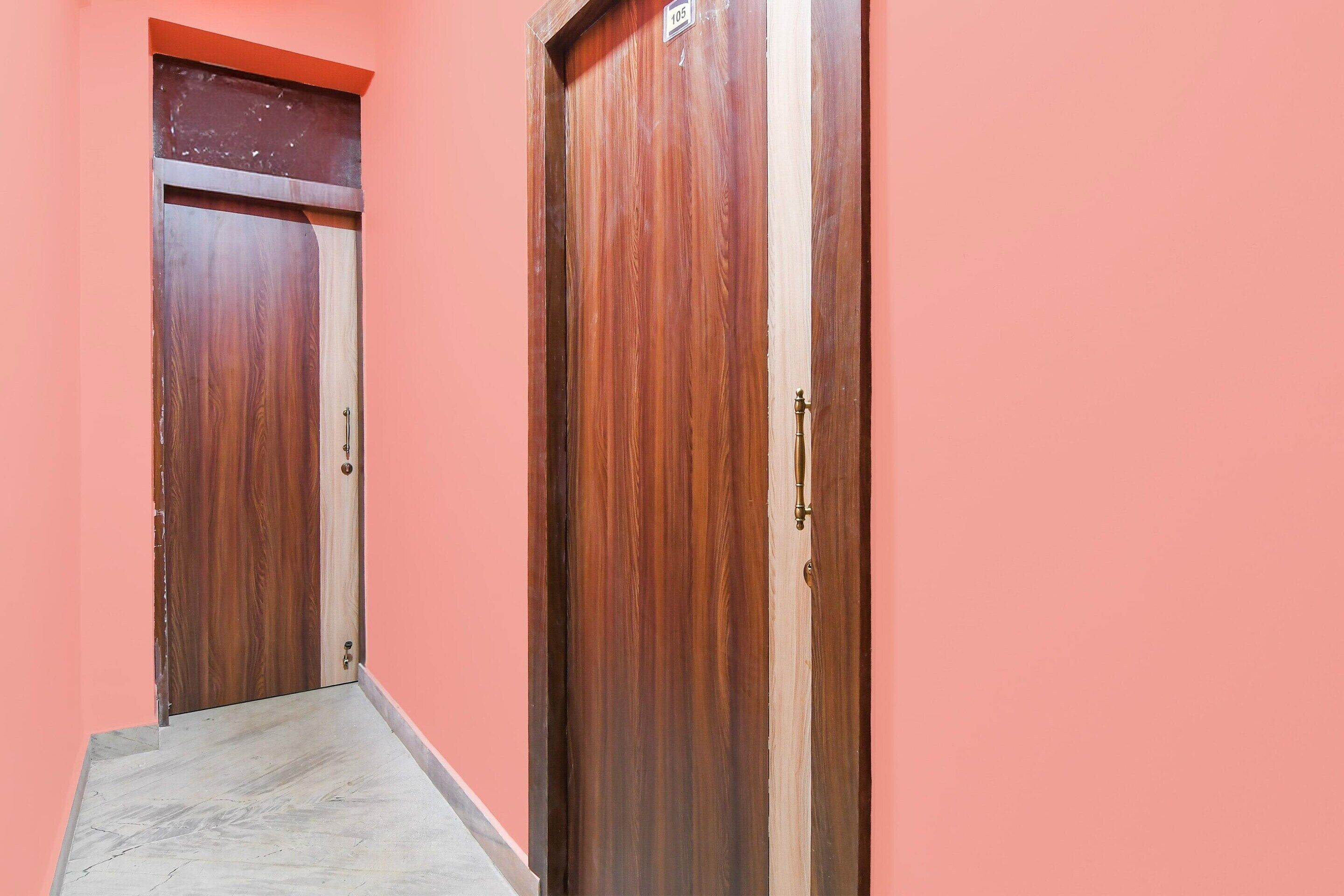 Un couloir avec deux portes en bois, dont l’une porte un numéro, et un sol en marbre.
