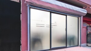 Eine Gebäudefassade mit einer großen Glasdoor, einem Metallvorsprung und roter und weißer Verkleidung.