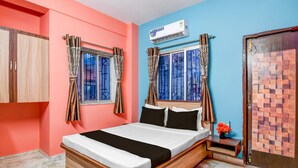 Ein Schlafzimmer mit Bett, Vorhängen, einer Klimaanlage und einer Tür mit einem gemusterten Design.