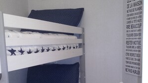 Ein Etagenbett mit sternenmusterbezogener Bettwäsche, ein kleiner Nachttisch mit Lampe und ein motivierender Wandplakat.