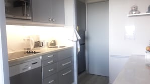 Eine kleine Küche mit Mikrowelle, Kaffeemaschine und Kühlschrank.