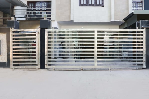 A gated entrance with a metal gate and a building with a balcony in the background.