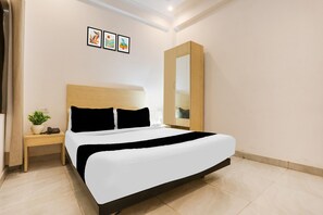 A hotel room with a bed, a nightstand, a mirror, and three framed pictures on the wall.