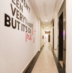 Un pasillo de hotel con una cita inspiradora en la pared, un extintor y un ascensor.