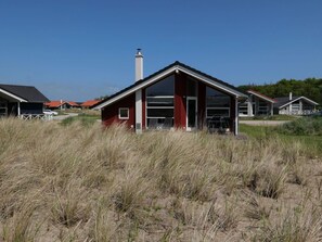 A modern building with a red facade, large windows, and a chimney. - 4 Star Holiday Home in Grossenbrode (Grossenbrode)