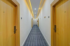 Un pasillo de hotel con puertas de madera, suelo alfombrado e iluminación empotrada.