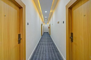 A hotel hallway with wooden doors, a carpeted floor, and recessed lighting.