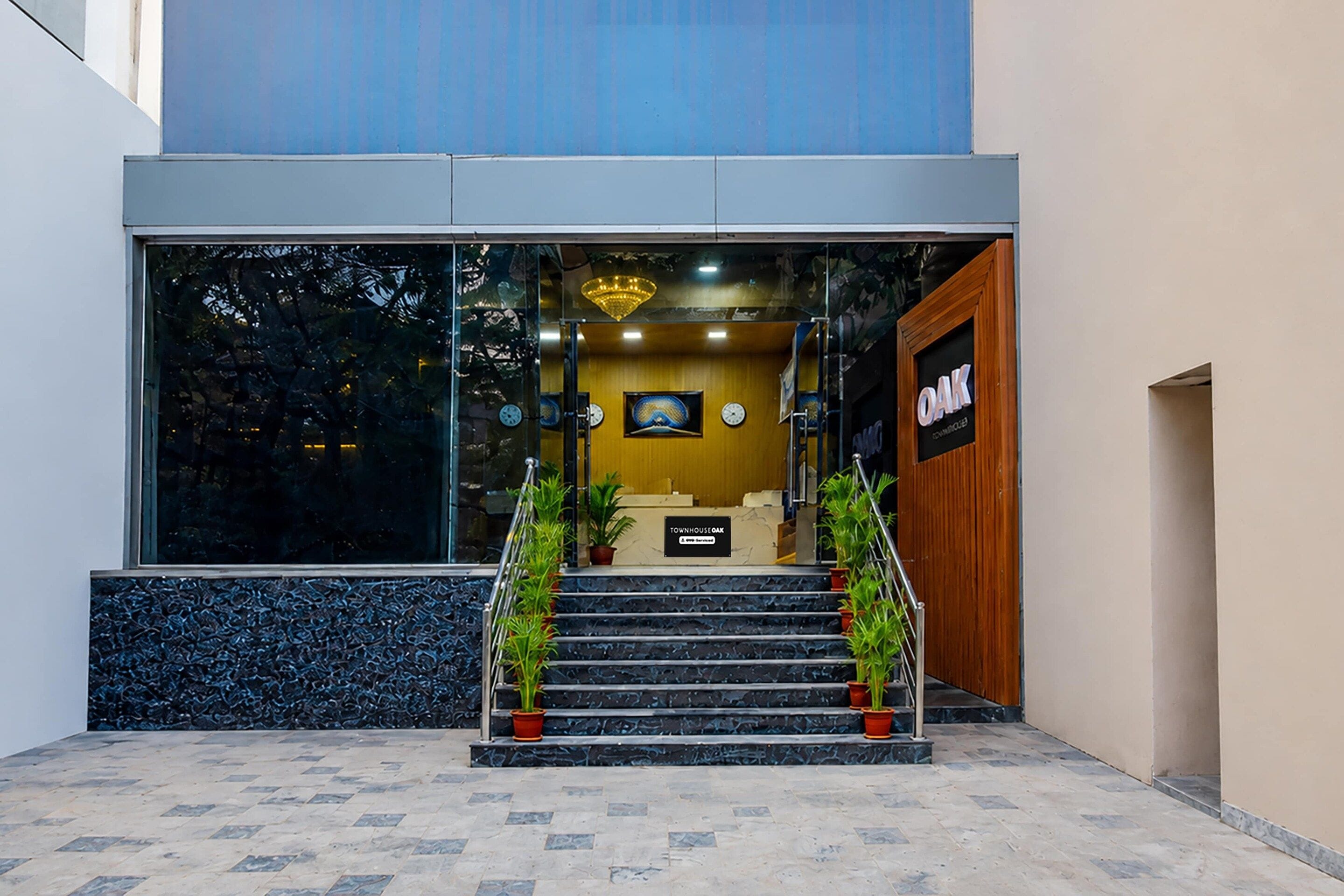 L’entrée d’un hôtel, avec un escalier, un comptoir d’accueil et une enseigne indiquant « OAK ».
