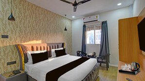 A hotel room with a bed, bedside table, lamp, and a window with curtains.