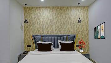 Um quarto com uma cama, duas mesas de cabeceira, um criado-mudo, telefone fixado na parede e luminária na parede.