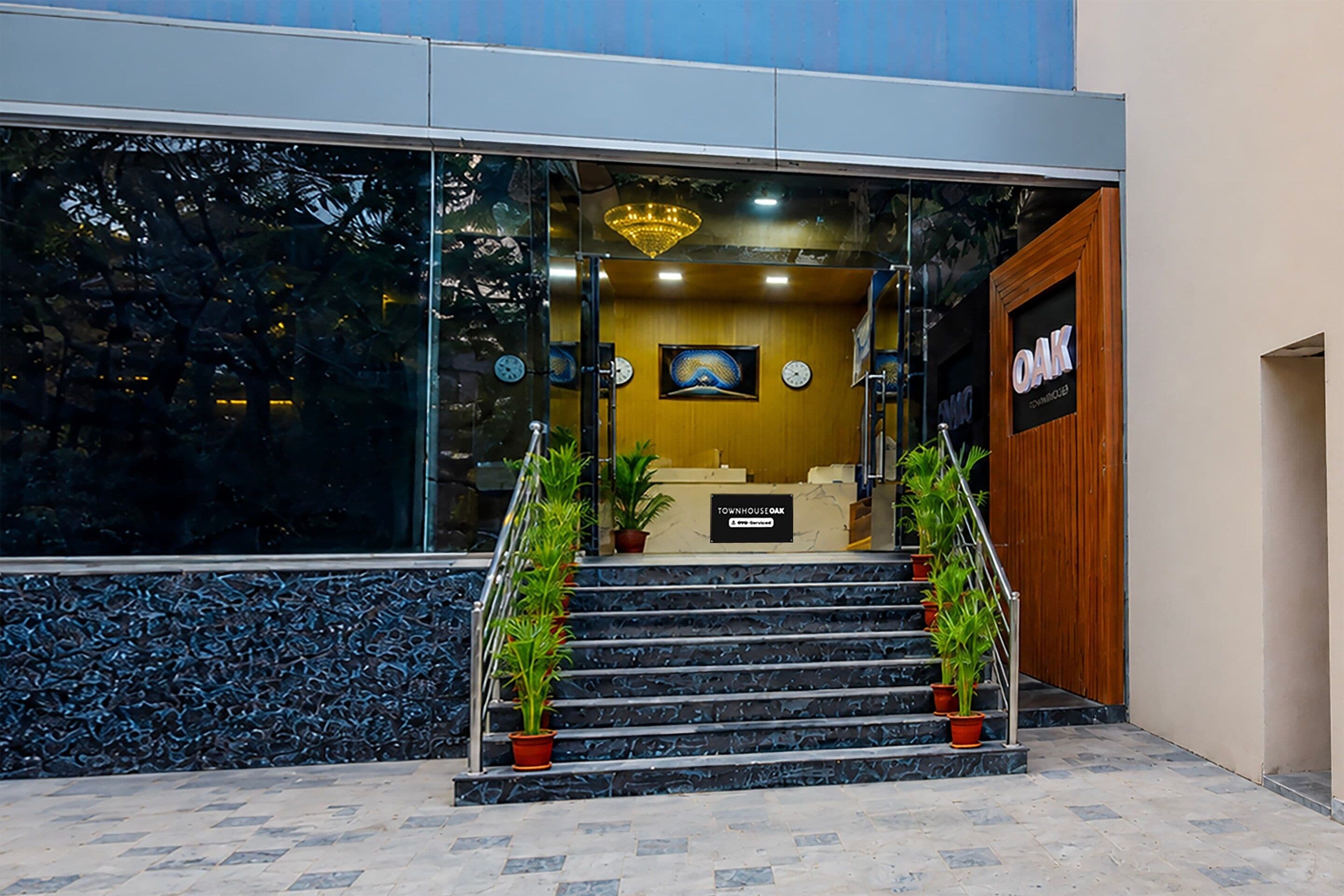 A reception area with a staircase leading to the entrance, a reception desk, and a clock on the wall.