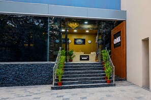 A reception area with a staircase leading to the entrance, a reception desk, and a clock on the wall.
