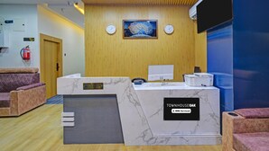A reception area with a marble counter, two clocks, a fire extinguisher, and a reception desk.