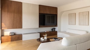 Una sala moderna con un sofá, una mesa de centro, un televisor y una cocina integrada.