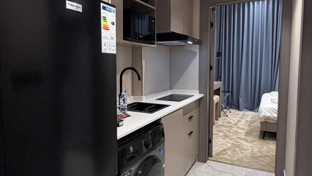 A compact hotel kitchen with a refrigerator, washing machine, and a small sink. - 101 Tara-jre Al Lweibdeh 2bdr Duplex Apartment (Amman)