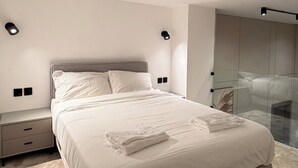 A modern bedroom with a bed, bedside tables, and a glass partition. - 101 Tara-jre Al Lweibdeh 2bdr Duplex Apartment (Amman)