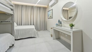 Hotellihuone, jossa on sänky, yöpöytä, peili ja ilmastointilaite.