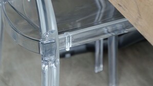 A clear plastic chair with a metal frame, a wooden table, and a concrete floor. - Cosy & lumineux – 3 pers – Paris centre (Paris)