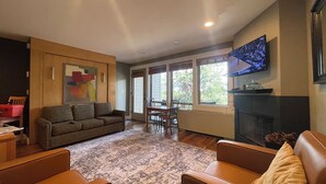 A living room with a sofa, chairs, a fireplace, a television, and a dining area. - Cozy Resort Hideaway (Bend)