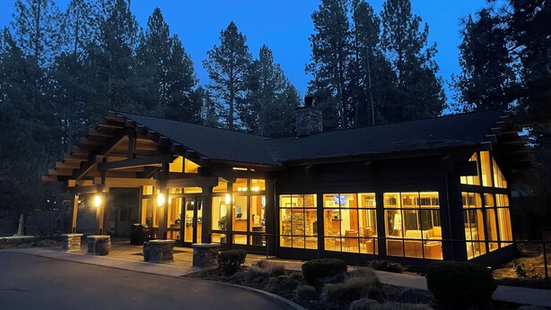 A modern building with a wooden exterior and large windows, surrounded by trees. - Cozy Resort Hideaway (Bend)