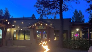 A building with a fire pit in the center, a sign for 'Morsel Maven Restaurant,' and outdoor seating. - Cozy Resort Hideaway (Bend)