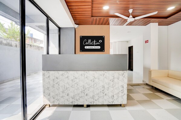A reception desk with a 'Collection' sign, a ceiling fan, and a checkered floor.