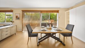 Un coin repas avec une table en bois, quatre chaises et une vue sur la verdure environnante.