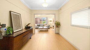 Un couloir avec une armoire en bois, une œuvre d’art encadrée, un luminaire au plafond, un canapé et une cheminée.