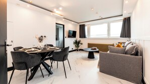 A modern living room with a dining area, a sofa, a TV, and a window. - Luxury One Bedroom Apartment, Holland Park and Next to Notting Hill - Pass the Keys (London)
