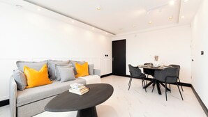 A modern living room with a sofa, coffee table, and dining area. - Luxury One Bedroom Apartment, Holland Park and Next to Notting Hill - Pass the Keys (London)