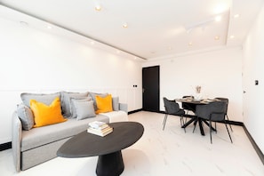A modern living room with a sofa, coffee table, and dining area. - Luxury One Bedroom Apartment, Holland Park and Next to Notting Hill - Pass the Keys (London)