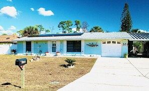 A residential house with a garage, a front yard with a small garden, and a mailbox. - 3 bed duplex with pool, by the water, centralized perfectly in Port Charlotte (Port Charlotte)
