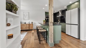 Eine moderne Küche mit einer zentralen Kochinsel, Holz-Barhocker und einer grünen Akzentwand.